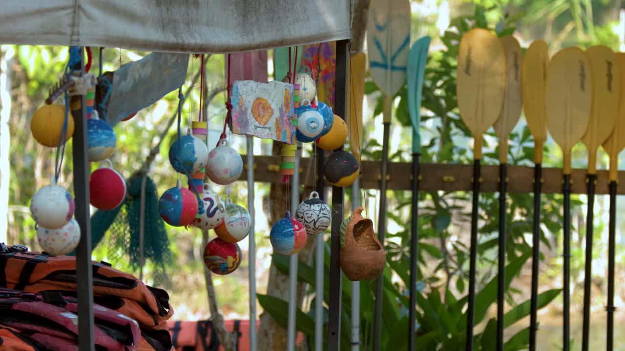 Statisk mellemnært billede af farverige bøjer og kajakudstyr ved en tropisk flodbredsstation.