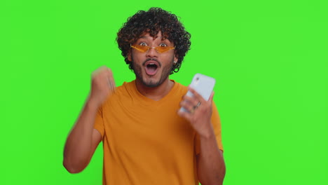 feliz emocionado ganador indio hombre usar teléfono inteligente decir wow sí descubrió gran gran ganancia buenas noticias lotería