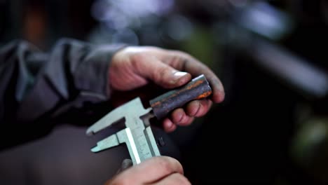 industrial worker with vernier caliper. factory man worker measuring steel detail with caliper at workshop