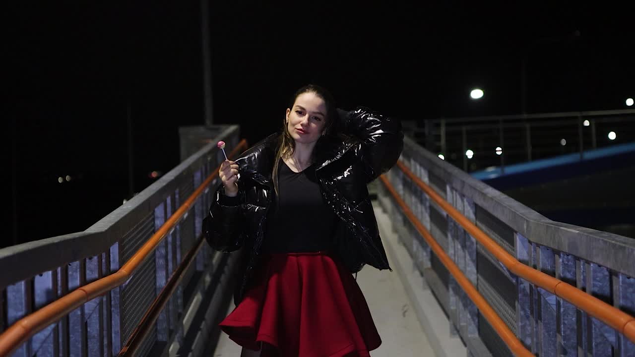 Beautiful young woman dancing alone at night in urban setting