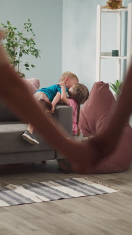 happy, friendly young family consists of mom, dad, daughter and son, little children rejoice, hug, kiss, woman and man in room take each other's hands