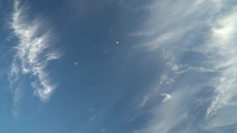 view of beautiful mysterious blue sky with fading clouds and moon with slow handheld camera movement slow motion