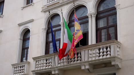 Venezianische,-Italienische-Und-Europäische-Unionsflaggen-Wehen-Auf-Dem-Berühmten-Alten-Balkon-In-Venedig