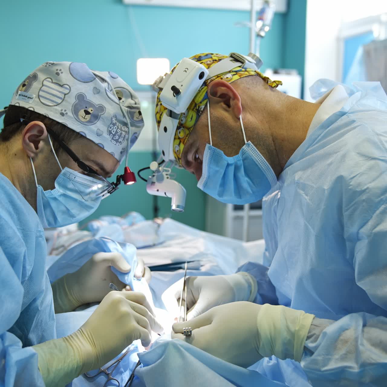 Hard-working surgeons bent over the patient on two sides of him. Doctors in funny caps and device flashlights on their heads operating metal tool at surgery
