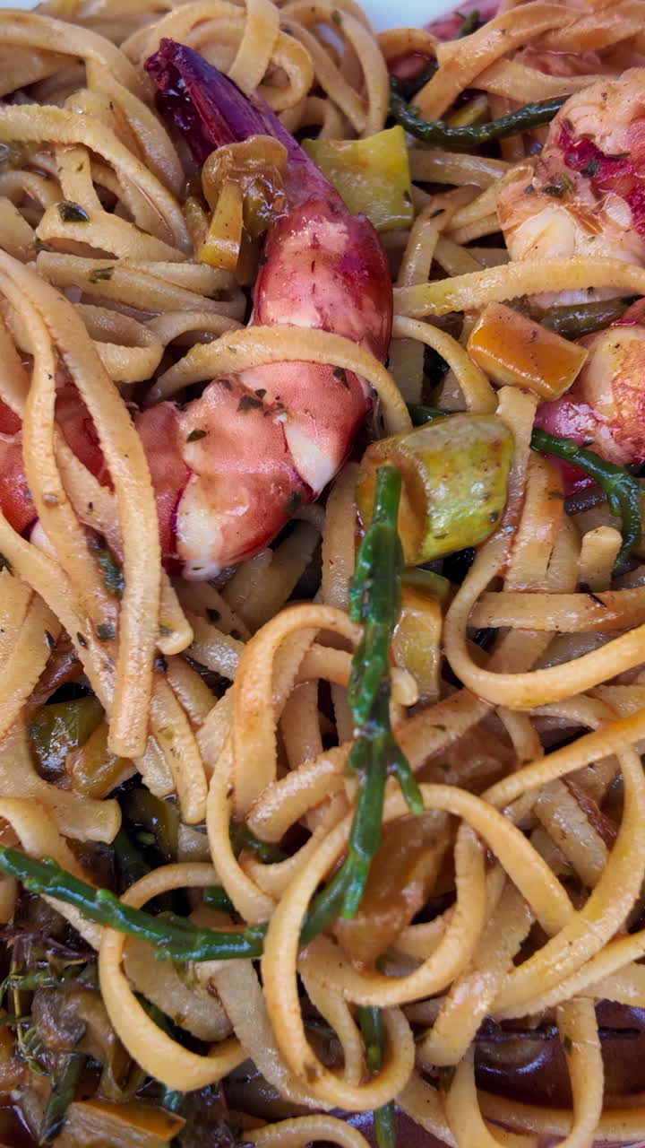 Close up of seafood pasta on a white plate at a restaurant. Vertical