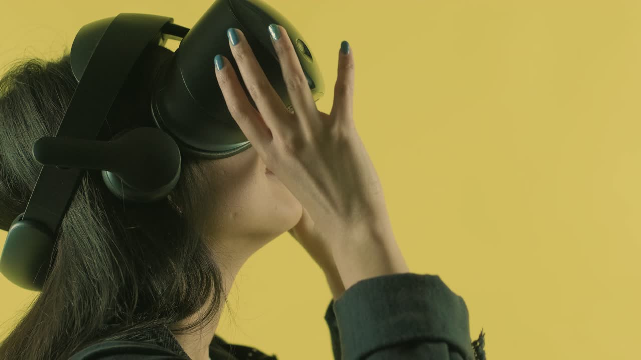 젊은 여성은 vr 헤드을 착용하고 주변을 둘러보고 vr 세계에서 얼마나 놀라운지 궁금합니다. 노란색 배경에 가상 현실 헬