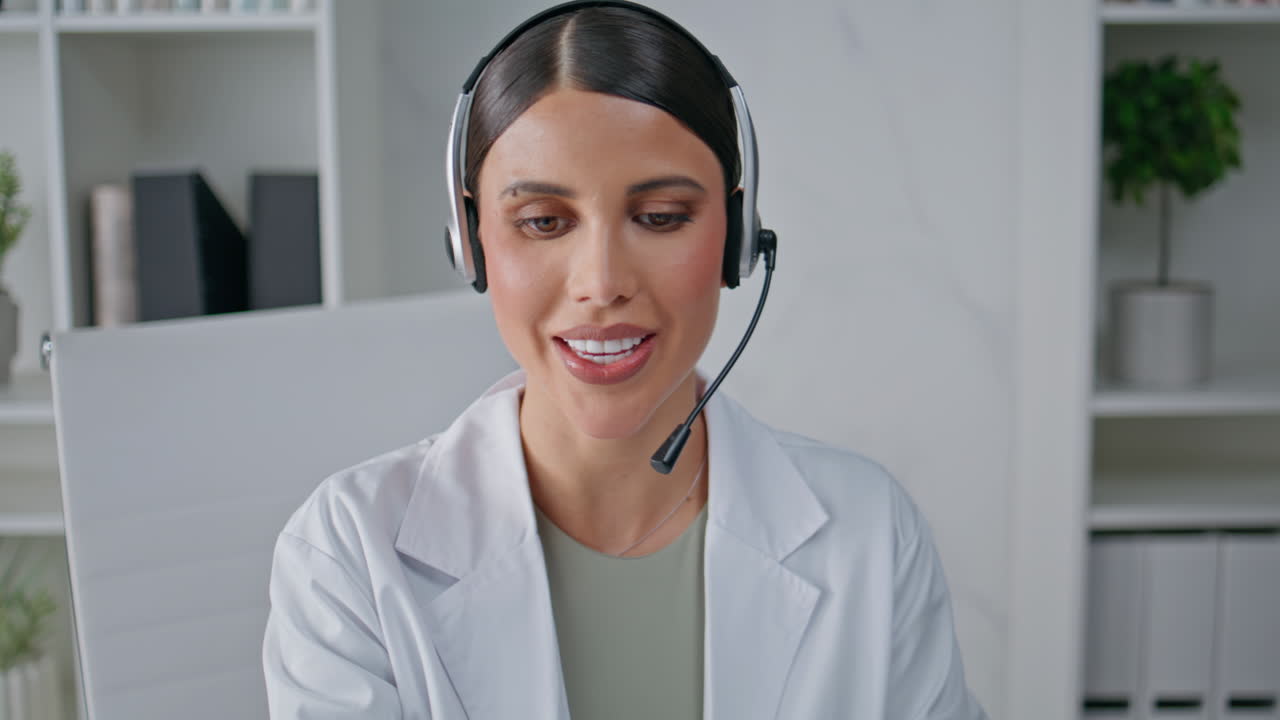 Woman physician listening headset at remote consultation in healthcare clinic