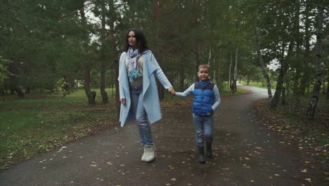 mother and son walking in a park on a rainy autumn day