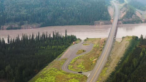 Car-driving-to-a-rest-area-near-Bridge-over-Tanana-river-in-Alaska-Range---The-landscape-around-Alaska-Highway-on-summer-foggy-day,-Alaska,-USA