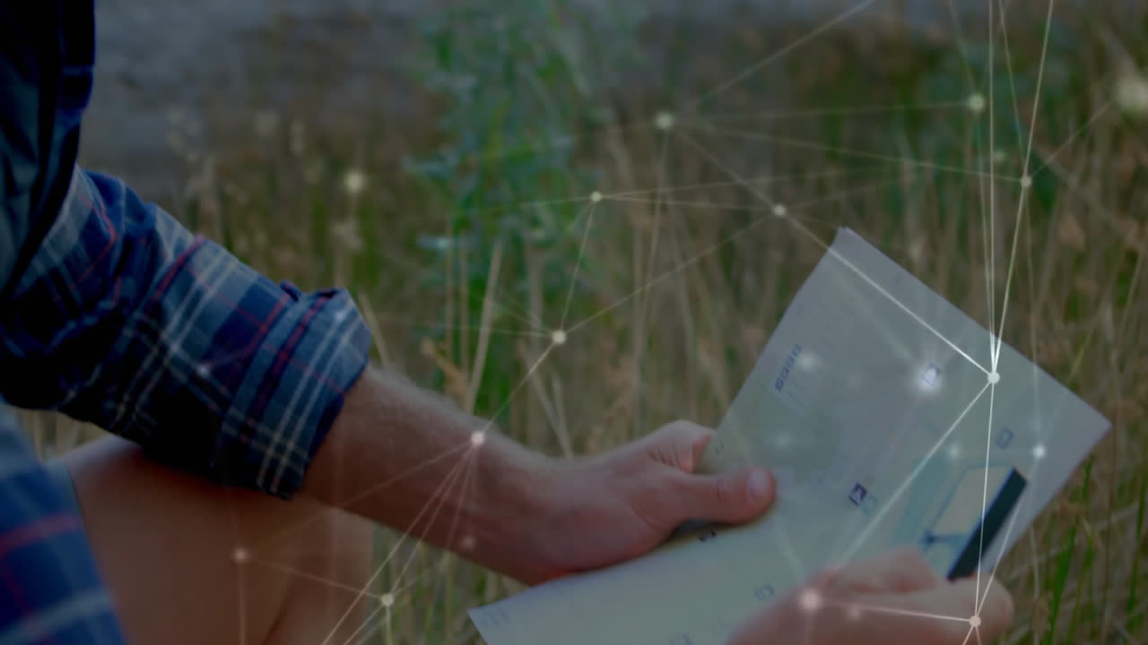Man holding folded map over outdoor field, showing glowing network nodes and lines for technology