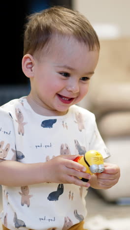 beautiful smiling baby holding a toy. kid plays with a toy cheering joyfully. blurred backdrop. vertical video