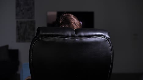 rear view of unrecognizable person sitting in armchair in dark office