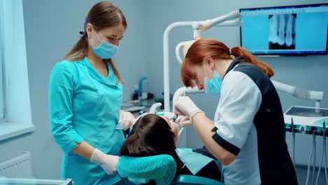 dentist with assistant treat patient's teeth. dental procedure in the modern stomatology office. female dentist working in patient oral cavity.