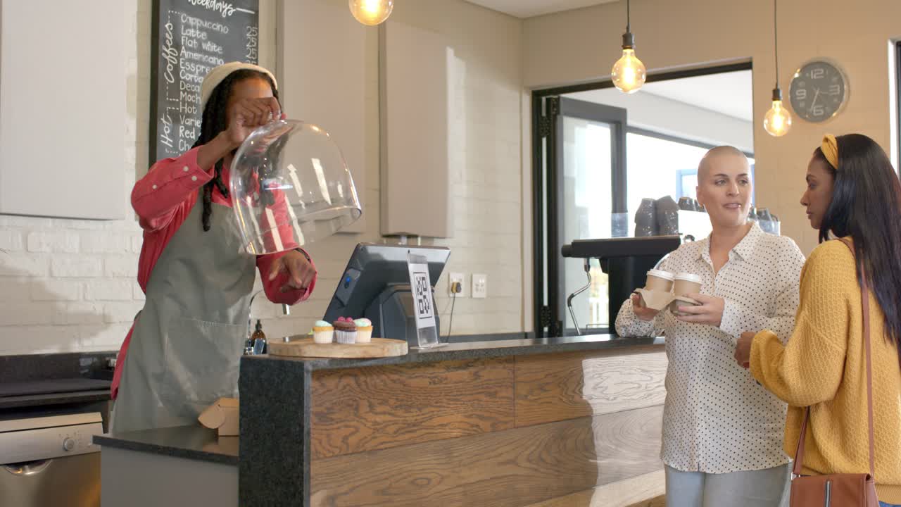 African American barista serving at counter friends holding cups lifting dome grabbing pastry box