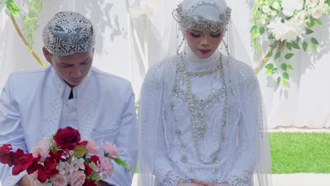 indonesian wedding ceremony: bride and groom in traditional white attire