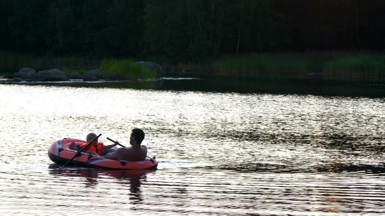 Happy laughing four year old girl rowing with her dad on calm lake on a summer evening, STATIC SLOW MOTION