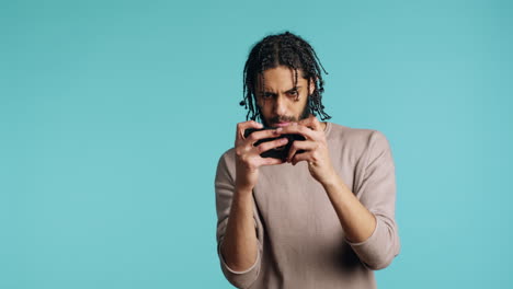 joyous gamer enjoying game on phone, excited about win, studio background