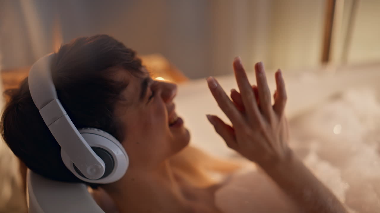 Primo piano di una modella con le cuffie che si rilassa con una sensazione da spa in un'atmosfera serale spensierata con candele.