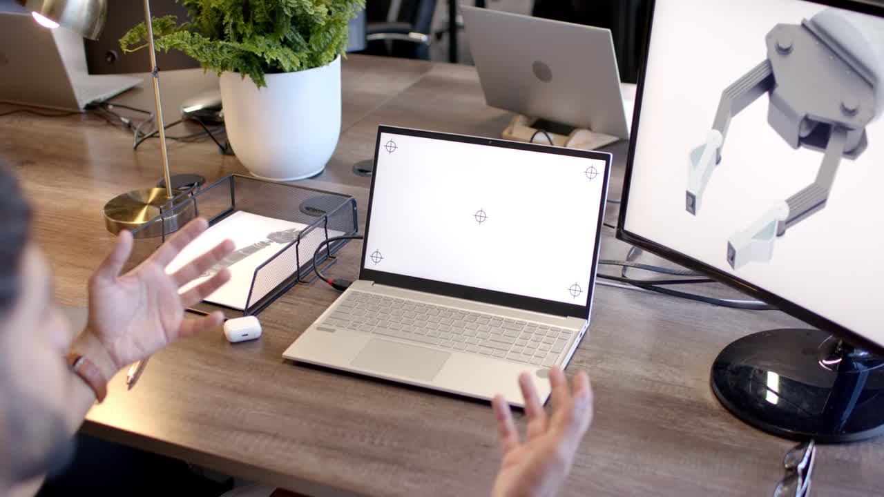Gesturing at laptop screen, person discussing robotic design in modern office, copy space