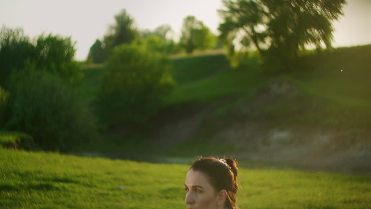 una mujer en cuclillas con pesas en el parque al atardecer levantando pesas delante de ella. entrenamiento con pesas. motivación