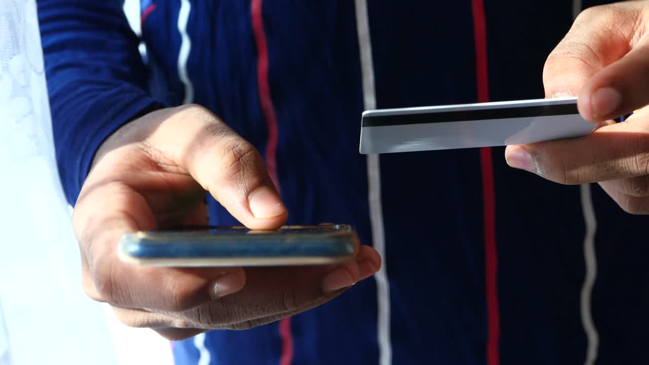 persona que utiliza un teléfono inteligente y una tarjeta de crédito para el pago móvil