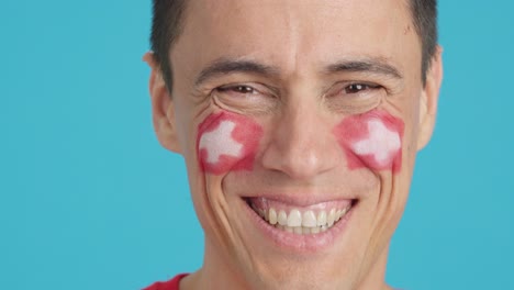 man with a swiss flag painted on the face smiling