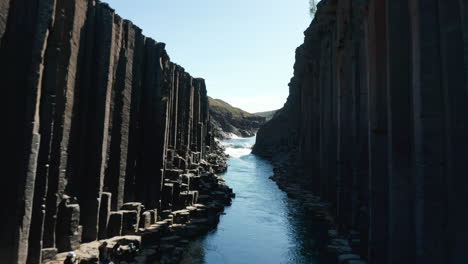 Aerial-view-of-Jokulsa-river-in-Vatnajokull-national-park-streaming-through-basalt-columns.-Drone-view-of-Studlagil-Canyon-with-basalt-columns-and-glacier-water-river-between-two-lava-walls