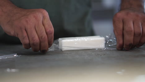 close-up of male hands, dirty from work, packaging a bar of soap