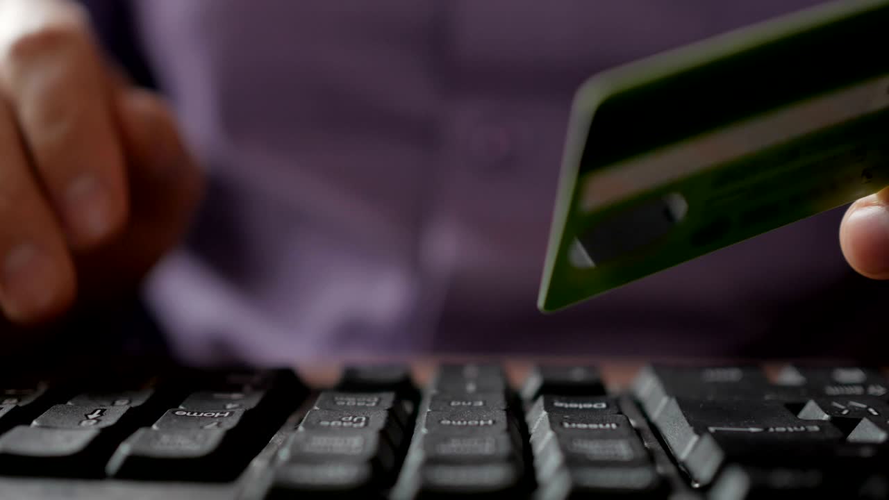 pagar con una tarjeta de crédito en línea, comprar. manos masculinas con tarjeta de crédito durante las compras a través de internet. teclado de computadora. primer plano. hombre de negocios hizo un pago electrónico.