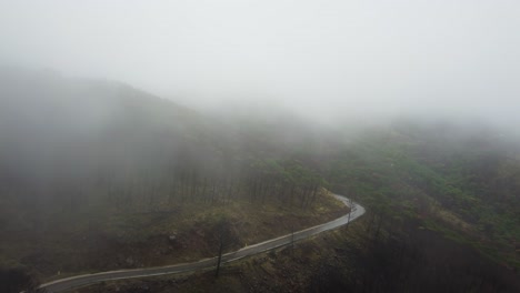 dangerous mountain road on foggy horror day, scary scene, aerial view