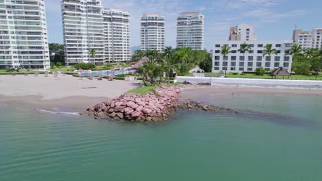 dronie of a wave breaker with palm trees in the hotel zone