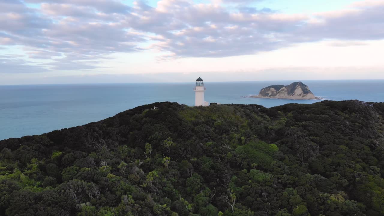 órbita aérea del faro de east cape ubicado en una colina boscosa, costa este, distrito de gisborne, nueva zelanda