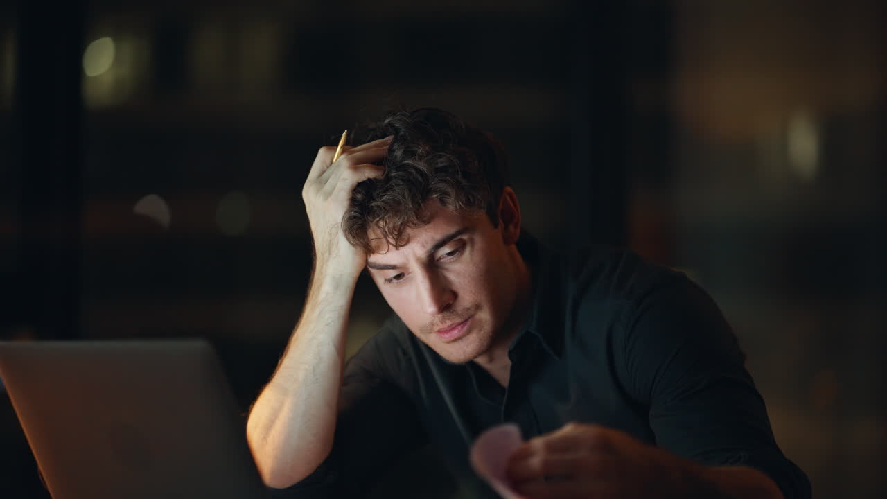 Overworked employee unmotivated work overtime at dark agency workplace closeup