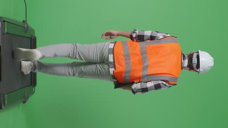 back view of full body asian male engineer with safety helmet holding a tablet while walking in the green screen background studio