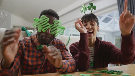Portrait-of-happy-diverse-couple-wearing-clover-shape-items-and-having-video-call