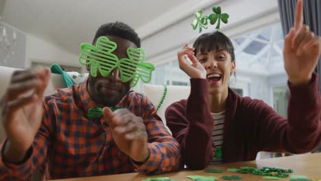 retrato de una feliz pareja diversa que usa artículos en forma de trébol y tiene una videollamada