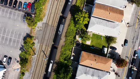 aerial footage following train of oil cars as passenger light rail car overtakes.