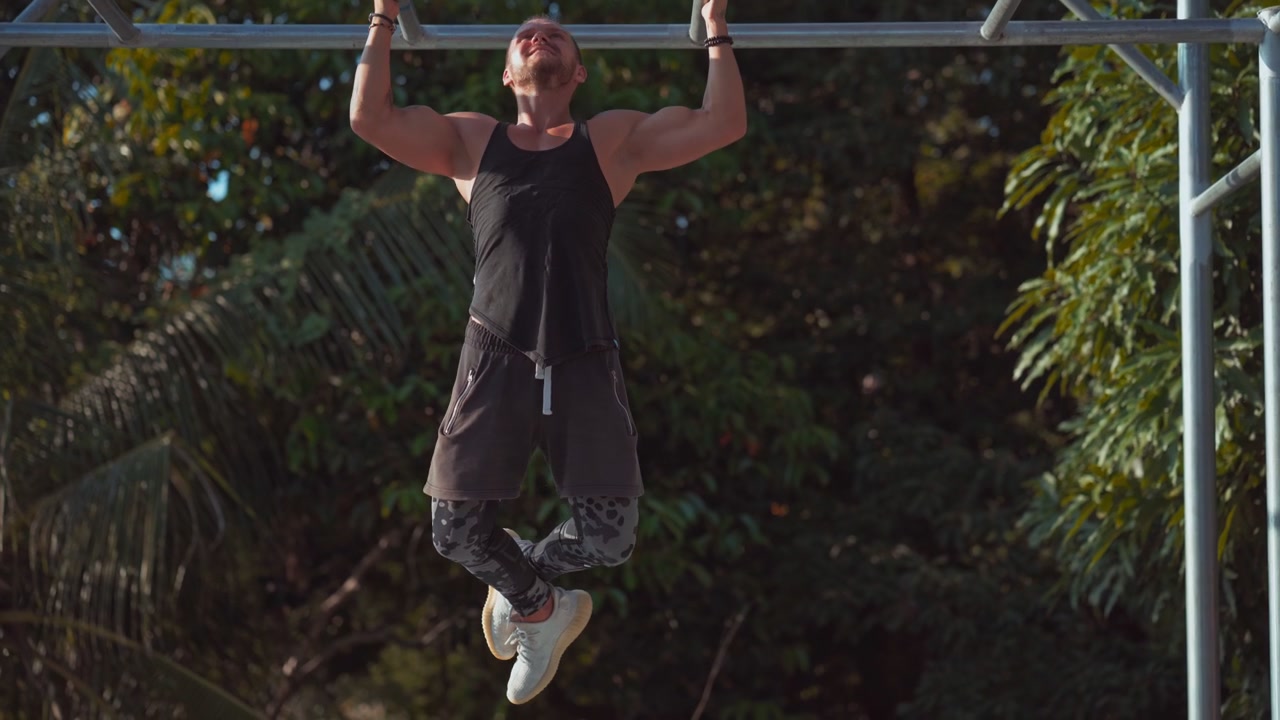 Muscular Man Performing Pull-Ups on Outdoor Calisthenics Bar