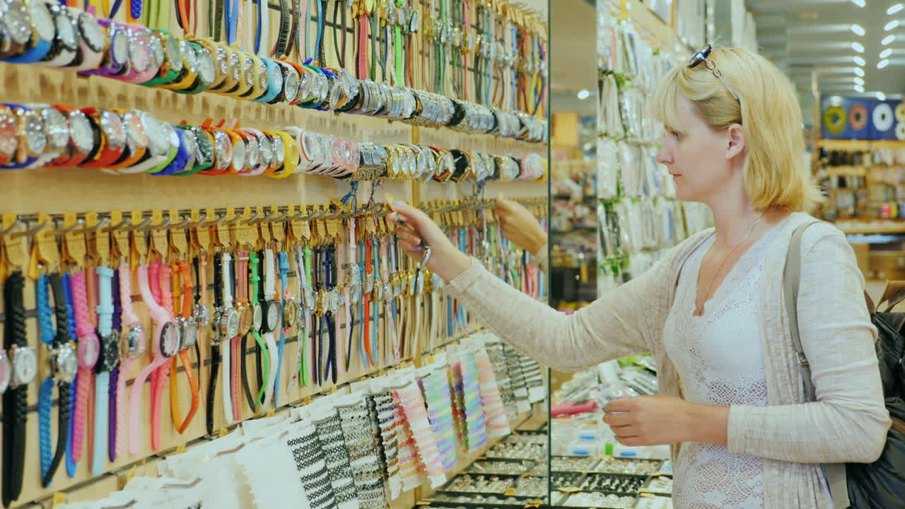 un joven turista elige un reloj en una tienda de regalos en la playa