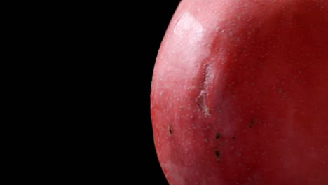 closeup video of rotating red pomegranate on black background