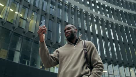 man using smartphone in front of modern building