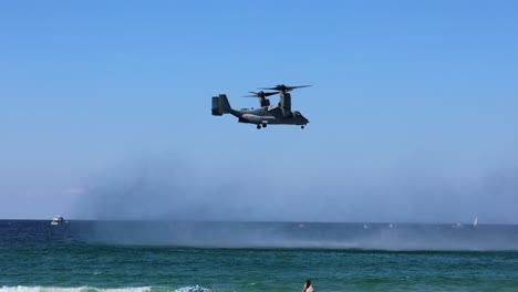 helicopter maneuvers over ocean, spraying water