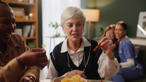 elderly women eating chips with caregiver