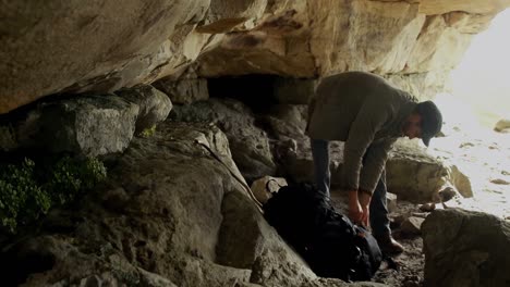 male hiker standing with backpack in the cave 4k