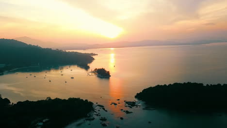 the sunrise during golden hour over a bay with a few boats in langkawi malaysia