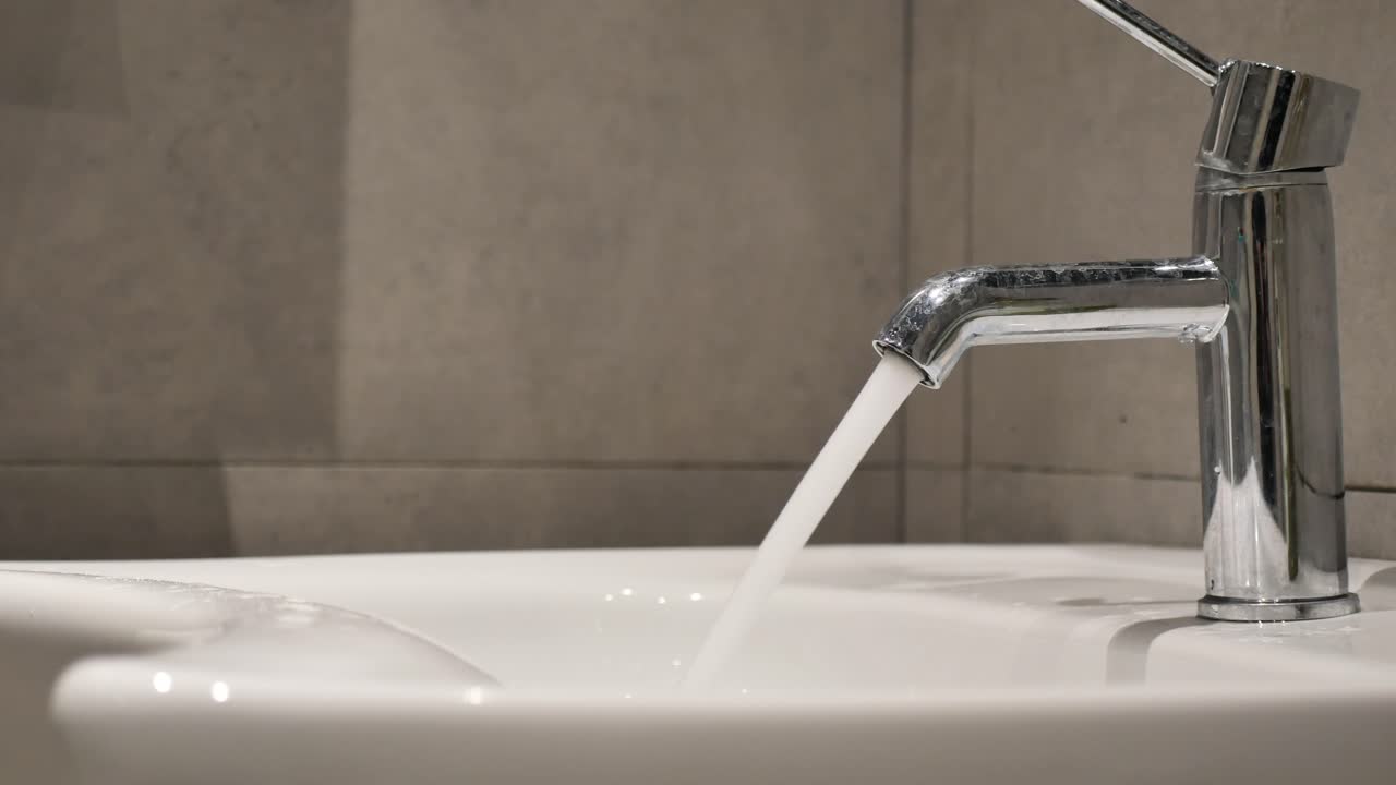 Water flowing from a chrome faucet into a white sink