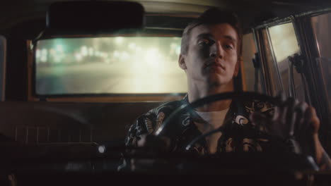 young man driving through city streets during late night