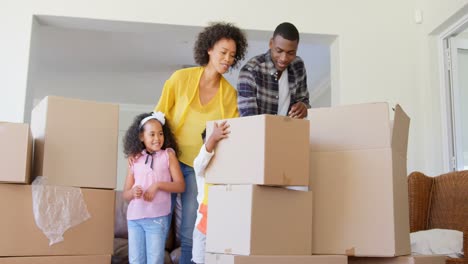 Front-view-of-black-family-unpacking-cardboard-boxes-at-comfortable-home-4k