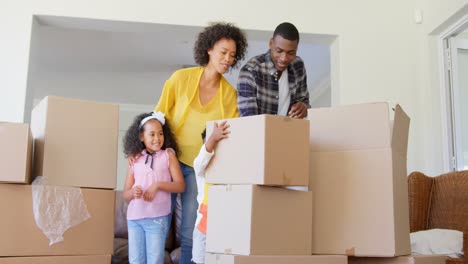 vista frontal de una familia negra desempaquetando cajas de cartón en un hogar cómodo 4k