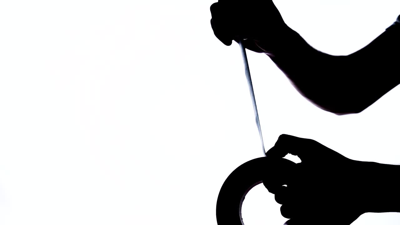 트 테이프 롤을 어내는 사람의 손의 클로즈업. 검은색과 색, 고립